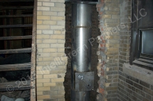 The new chimney liner is installed inside the existing chimney. Due to the location of the chimney, the brick side had to be removed first. Another "clean out door" at bottom.