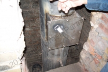 Chimney liner resting on footing at the bottom of the chimney stack, which went below grade originally to meet the stack used when the boiler used only oil.  A "clean out door" at the bottom of the stack. A bracket is installed at the top and bottom of the new chimney liner inside the stack. The liner rests at the bottom of the stack on a footing. On average the contractor can weld and install 20' of liner per day.