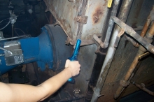 LL87/09 energy auditor uses a smoke stick to test air movement at the boiler door. A sealed door will improve the boiler's operating efficiency.  © 2015 IntelliGreen Partners LLC